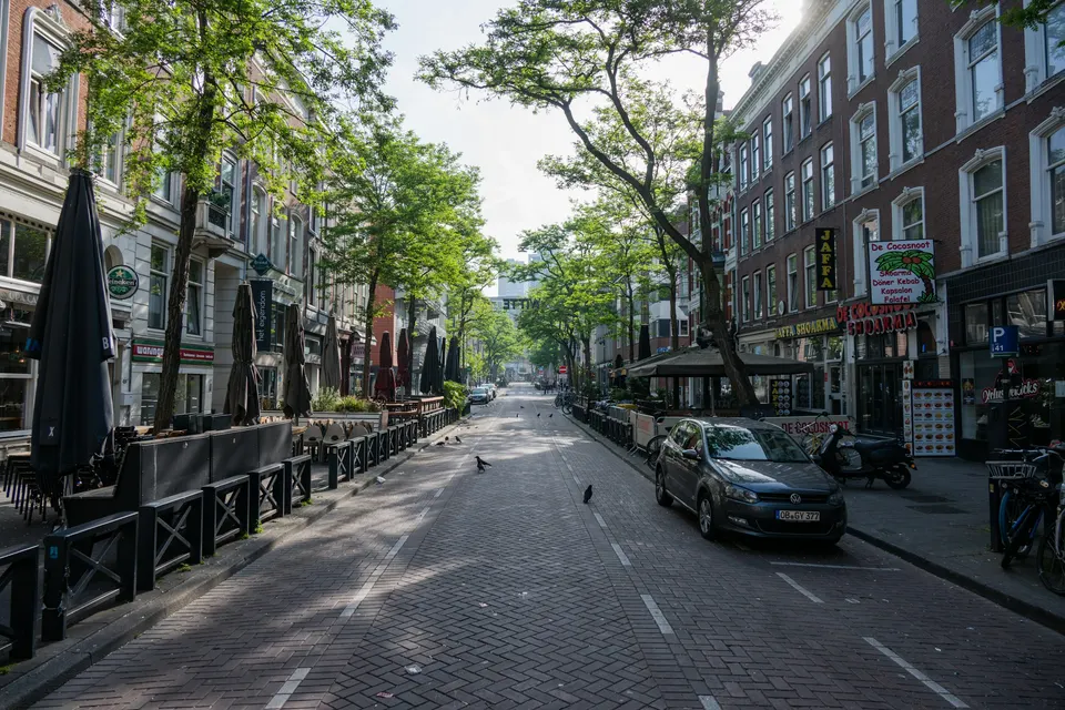 Rua arborizada e tranquila com mesas de café ao ar livre